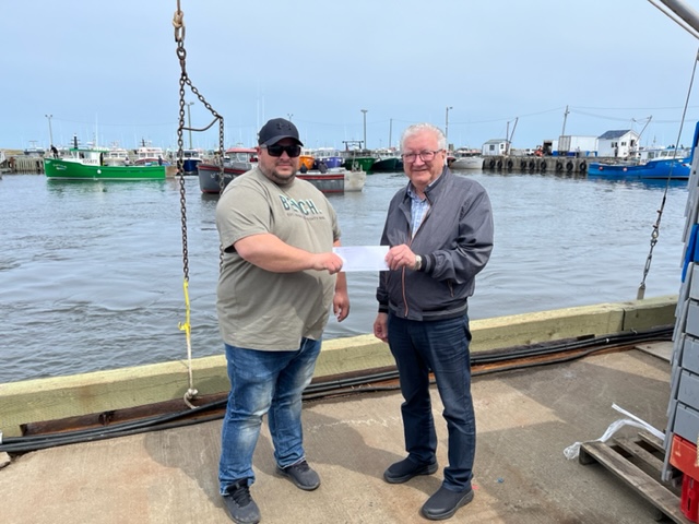 La communauté des pêcheurs côtiers de Pigeon-Hill remet un don de 60 000 $ à la Fondation communautaire.  Eric Dufour en fait la présentation à Jean-Charles Chiasson.